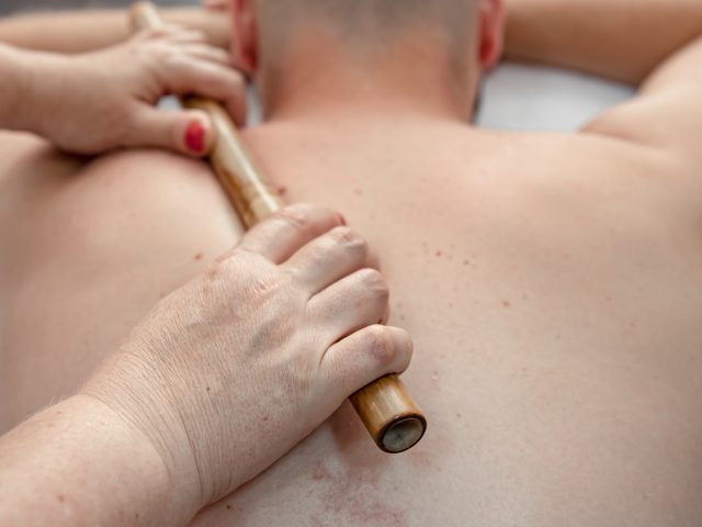 The masseur using massage bamboo sticks during treatment.